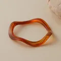 Close-up of amber wavy acrylic bracelet with translucent texture on stone backdrop - Amber Marble Wave Style (AB0026-3)
