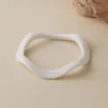 Vista dettagliata del bracciale in acrilico bianco ondulato su fondo beige con pietre naturali - Stile Onda Bianco Opaco (AB0026-5)