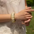 Chunky gold metal bangle with beige marble resin inlay worn in a natural outdoor setting - Beige Segmented Inlay Style (AB0039-1)