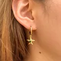 Gold starfish hoop earrings with green gemstone detail shown on model's ear - Starfish With Green Stone Style (KE1780)