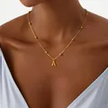 Close-up of golden letter A pendant necklace with beaded chain on a female model - Letter A