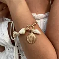 Golden sea shell and white snail bracelet on a woman’s wrist for a summer resort style - Gold Bracelet (2807)