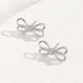 Close-up of minimalist silver bow earrings on white stone textured background - Silver Thin Wire Bow (BSSP009B)
