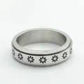 Detailed macro view of a stainless steel spinner ring featuring engraved daisy patterns - US 7 / Silver