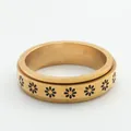 Detailed macro view of the gold spinner ring featuring black daisy floral patterns - US 7 / Gold