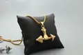 Detail of hand gripping dumbbell pendant in gold and silver finish on leather display - Gold