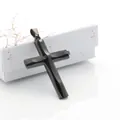 Detalle de un colgante de cruz negra de doble capa con bordes facetados en caja de regalo - Negro de moda