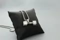 Nahaufnahme einer Hantel-Halskette aus Edelstahl auf einem schwarzen Samtkissen-Display - Silber