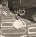 Pendentif rond en acier inoxydable poli sur chaîne box posé sur un magazine - Argent (60cm)
