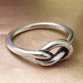 Macro shot of polished silver knot ring showing sleek metallic texture on satin - US 6 / Steel