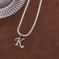 Détail macro d'une chaîne serpent argentée avec pendentif lettre K majuscule polie - Lettre K