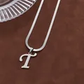 Gros plan du pendentif lettre T en argent avec chaîne serpent sur fond velouté - Lettre T