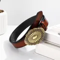 Vintage red-brown leather belt with embossed brass oval buckle on white books - Round Sunburst Buckle Style / Amber / 100