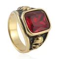 Macro detail of men's gold punk ring with red square stone and skull carvings - Gold Red Stone