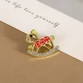 Close-up of golden rocking horse brooch with red enamel and sparkling rhinestones - Rocking Horse Style / Gold