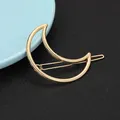 Close-up of golden crescent moon hair clip with hollow geometric lines on black leather - Minimalist Crescent Moon Style