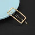 Detail of a minimalist gold-colored rectangular geometric alloy hair clip on a blue plate - Rectangular Geometric Style