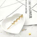 Dettaglio di un fermaglio per capelli a cuore dorato su un piatto in ceramica bianca - Stile Cuore