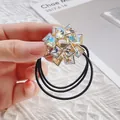 Détail d'un élastique à cheveux fleur en cristal avec triple liens et base dorée - Cristal AB