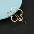 Detailed view of a golden four-leaf flower metal hair clip on a textured surface - Four-Petal Flower Style