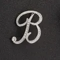Primer plano de broche letra B plateado con cristales brillantes sobre cuero negro - Letra B / Plata B