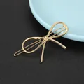 Close-up of a minimalist golden alloy butterfly hair clip on a textured black surface - Simple Bowknot Style