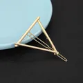 Detail of a geometric gold triangular hair clip with a wavy metal pin on leather background - Simple Triangle Style