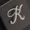 Primer plano detallado de un broche plateado letra K con cristales en caja de regalo - Letra K / Plata K