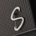 Primer plano de broche de letra S plateada con pedrería brillante sobre cuero negro - Letra S / Plateado Forma S