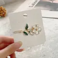 Detailed close-up of a white flower hair clip with golden edges on a display card - Hair Clip / White Flower