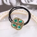 Detalle de dije dorado con cristales en gomas de pelo negras de alta elasticidad - Cuadrado Verde