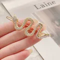 Pasador de pelo de serpiente dorado con brillantes pedrería en fondo minimalista - Modelo con Diamantes de Imitación Dorados