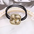 Detalle de elegante coletero cuadrado de cristal dorado con cuerda elástica negra - Cuadrado Champán