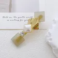 Primer plano detallado de pinza geométrica dorada con piedra de opalo y perla sintética - Estilo Café Claro Mate