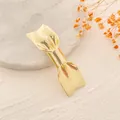 Detailopname van een elegante gouden metalen strik haarspeld op een getextureerd vlak - Gouden Strik