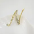 Broche de letra N dorado brillante con pedrería de cristal sobre plato de cerámica blanca - Letra N / Dorado