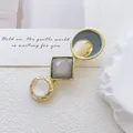 Detalle de una pinza para el cabello dorada con resina gris y piedra de ojo de gato blanca - Estilo Combinación Geométrica Multicolor