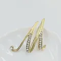 Elegante broche letra M dorada con cristales brillantes sobre una bandeja blanca cerámica - Letra M / Dorado