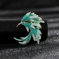 Vista macro de broche de pluma turquesa degradada con cristales en base dorada - Azul Fénix
