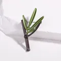 Detailed view of dark green bamboo leaf brooch with gold pin on white stone - Bamboo Design Style