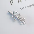 Detailed macro view of silver alloy flower hair clip with sparkling rhinestones and hollow design - Silver