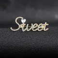 Detail shot of a gold-plated Sweet letter brooch encrusted with sparkling rhinestones - Golden Sweet Style