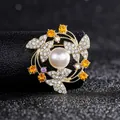 Macro shot of circular brooch with white pearl, rhinestone butterflies on golden base - Gold Butterfly