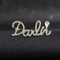 Macro shot of gold letter brooch with pavé rhinestones and a clear teardrop crystal detail - Golden Darling Style