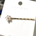 Schicker goldener Haarclip mit rosa Emaille-Blume und glitzerndem Strass auf Karte - Rosa Blume