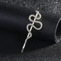 Macro detail of a silver snake bobby pin featuring green gem eyes and textured scales - Gold