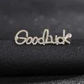 Macro shot of Goodluck letter brooch with sparkling rhinestones and teardrop crystal - Golden Goodluck Style
