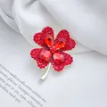 Elegant gold-tone four-leaf clover brooch with red rhinestones on silk fabric - Red