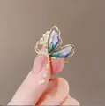 Elegante vlinderbroche van goudkleurig metaal met paars-groene vleugels en zirkoon - Blauw Paarse Vlinder met Kwastje