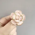 Elegante broche de camelia dorada con piedras de ojo de gato rosa en mano - Anillo / Rosa